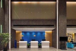 A reception area with a modern design, featuring a reception desk, seating area, and a television screen.