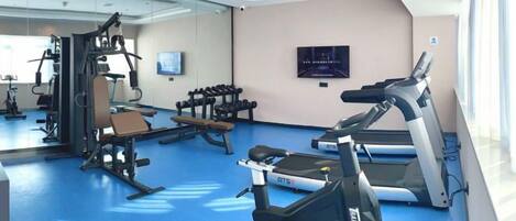 A gym with exercise equipment, a treadmill, and a mirrored wall.