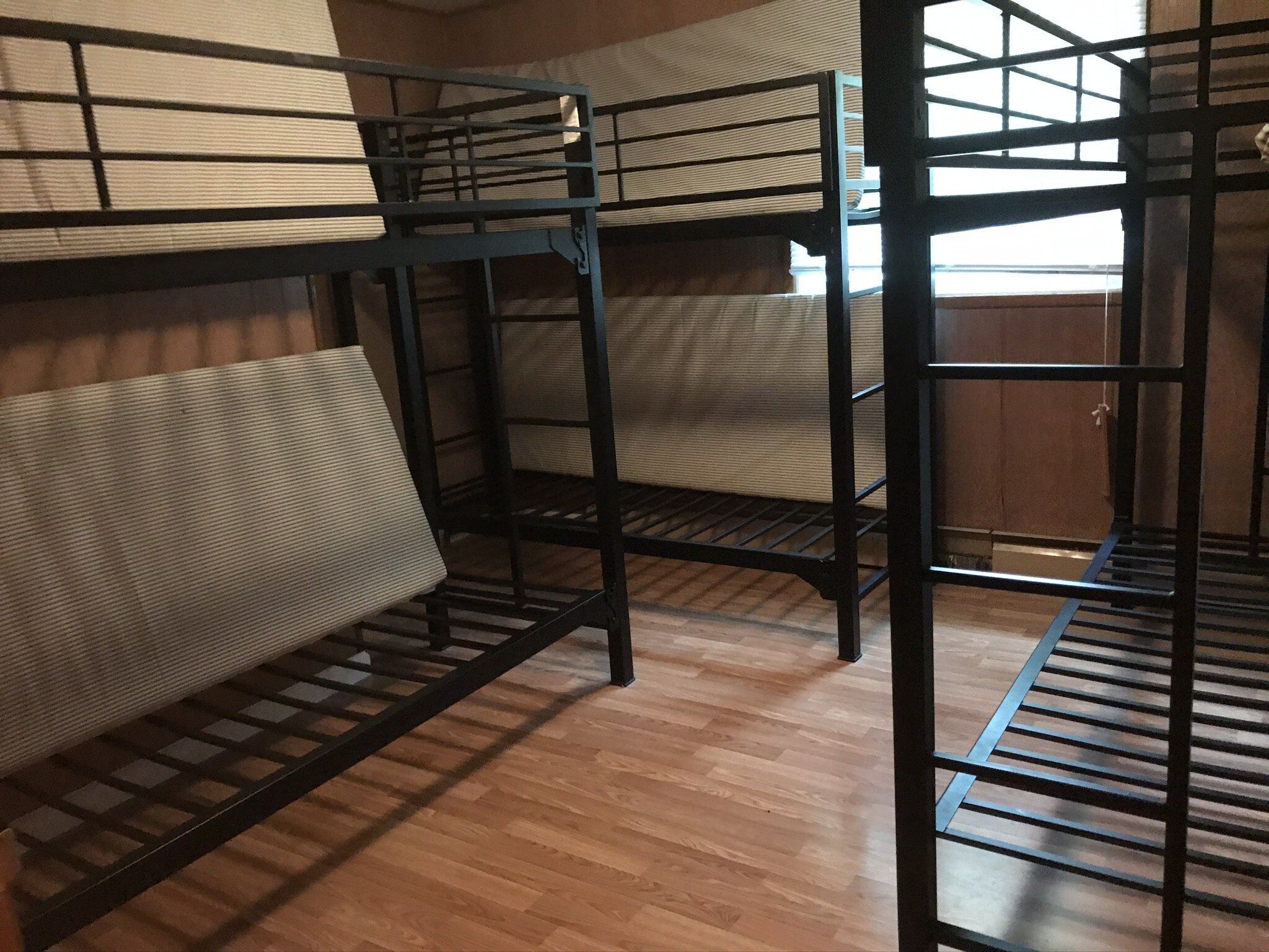 Dormitorio con literas, suelo de madera y barandillas de metal.