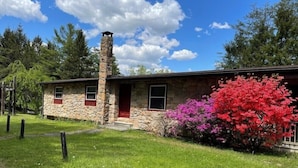 A stone building with a chimney, a red door, and windows with red frames.