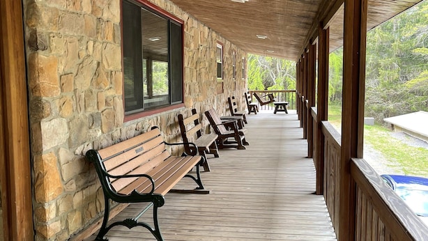 A covered wooden deck with stone walls and benches.