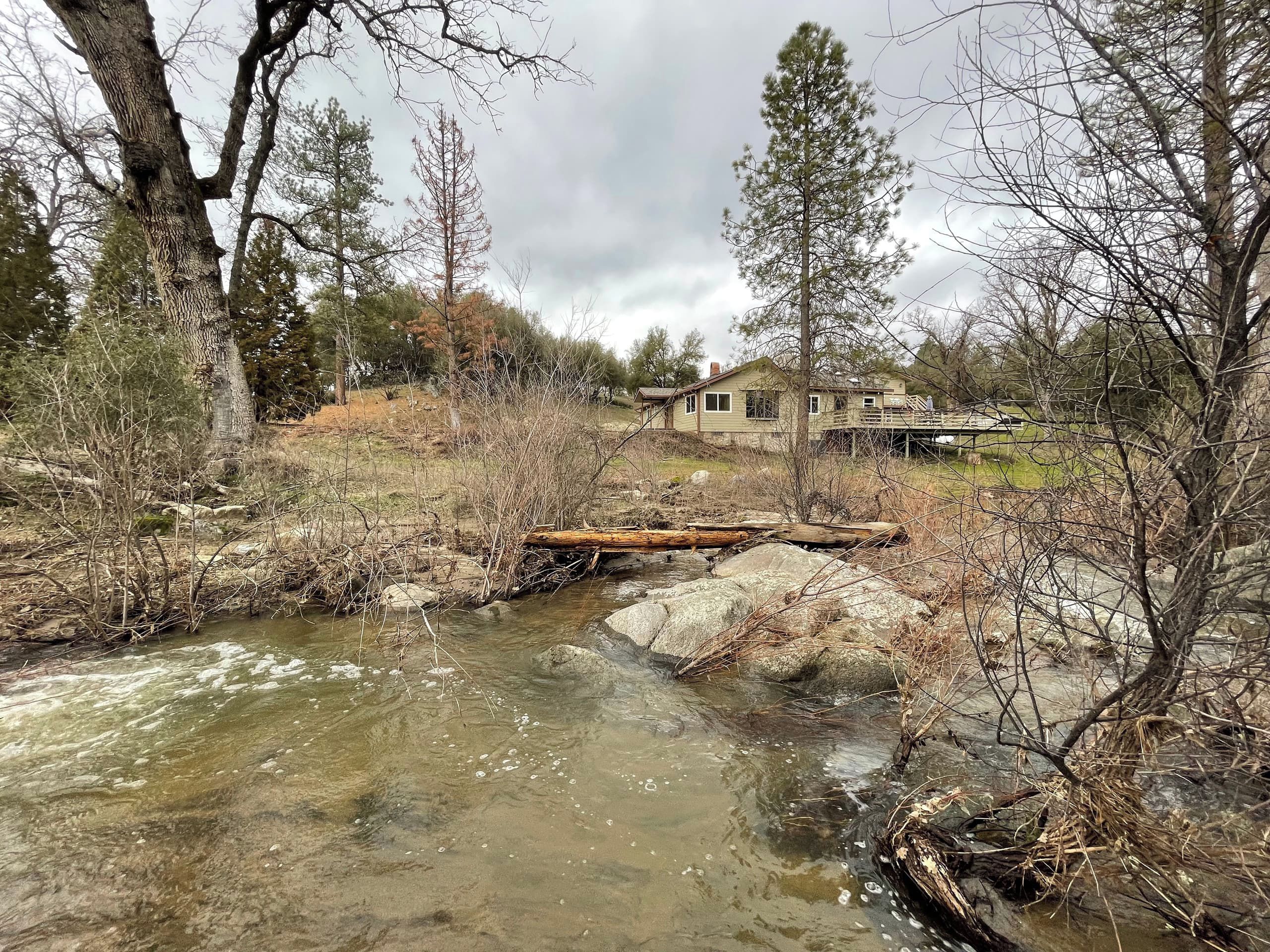 A house with a deck overlooking a stream.