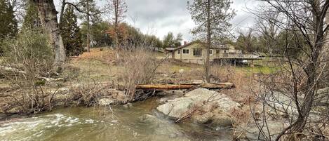 A house with a deck overlooking a stream.