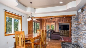 A spacious living area with a wooden dining table, chairs, and a stone fireplace. - 🛶 Cozy Creek Cabin near Yosemite & Bass Lake (Ahwahnee)