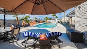Un espace aménagé au bord de la piscine, avec des chaises longues, une table et des parasols.