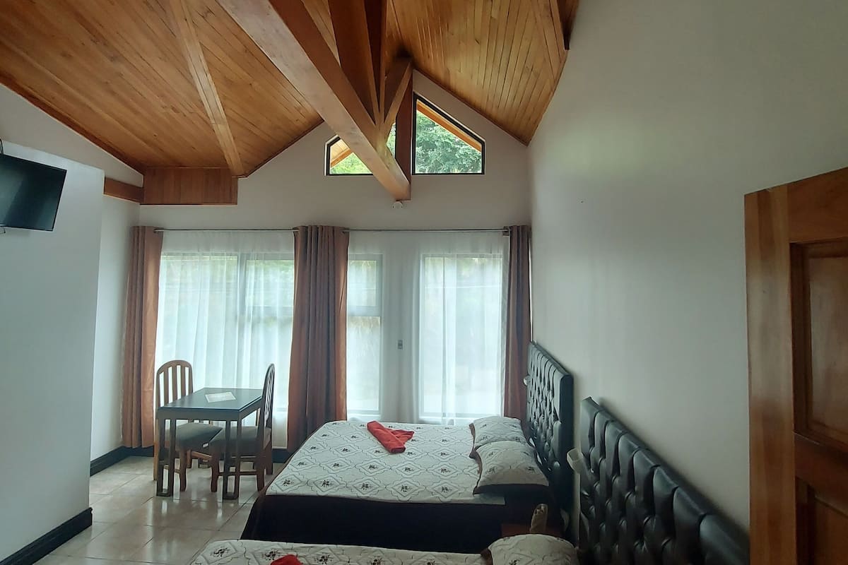 A room with two beds, a dining table, and a TV.