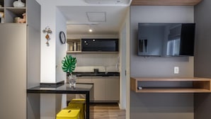 A compact kitchen with a black countertop, a yellow stool, and a potted plant. - Av0111 Studio Avanhandava (São Paulo)