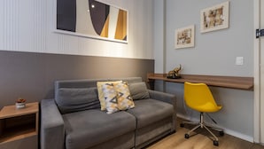 A modern living room with a grey sofa, a yellow office chair, and a wooden desk. - Av0111 Studio Avanhandava (São Paulo)