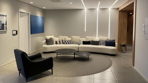 Un salon moderne avec un canapé aux lignes courbes, un fauteuil noir et une table basse ronde.