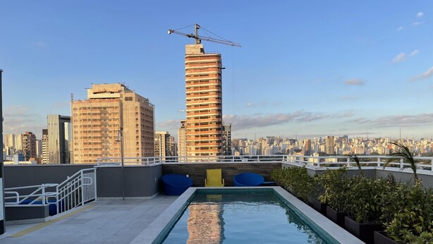 Une piscine sur le toit offrant une vue sur les toits de la ville, notamment sur un grand immeuble en construction.