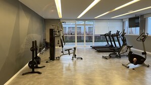 Une salle de sport moderne équipée de machines de cardio, d’appareils de musculation et de grandes fenêtres offrant une vue sur l’extérieur.