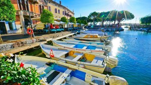 A canal with boats docked along the waterfront, a bridge in the background, and buildings with balconies. - Residenza al Ponte in Arco (Arco)