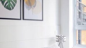 A bedroom with a bed, white walls, and two framed artworks. - Av0408 Studio Avanhandava (São Paulo)