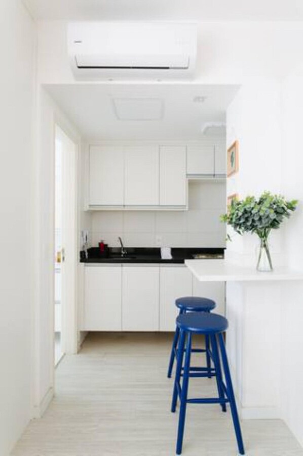 A modern kitchen with white cabinets, a black countertop, and a blue stool.
