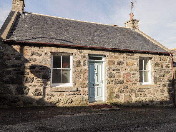 A stone house with a blue door, two windows, and a chimney. - 2 Seafield Place (Banff)