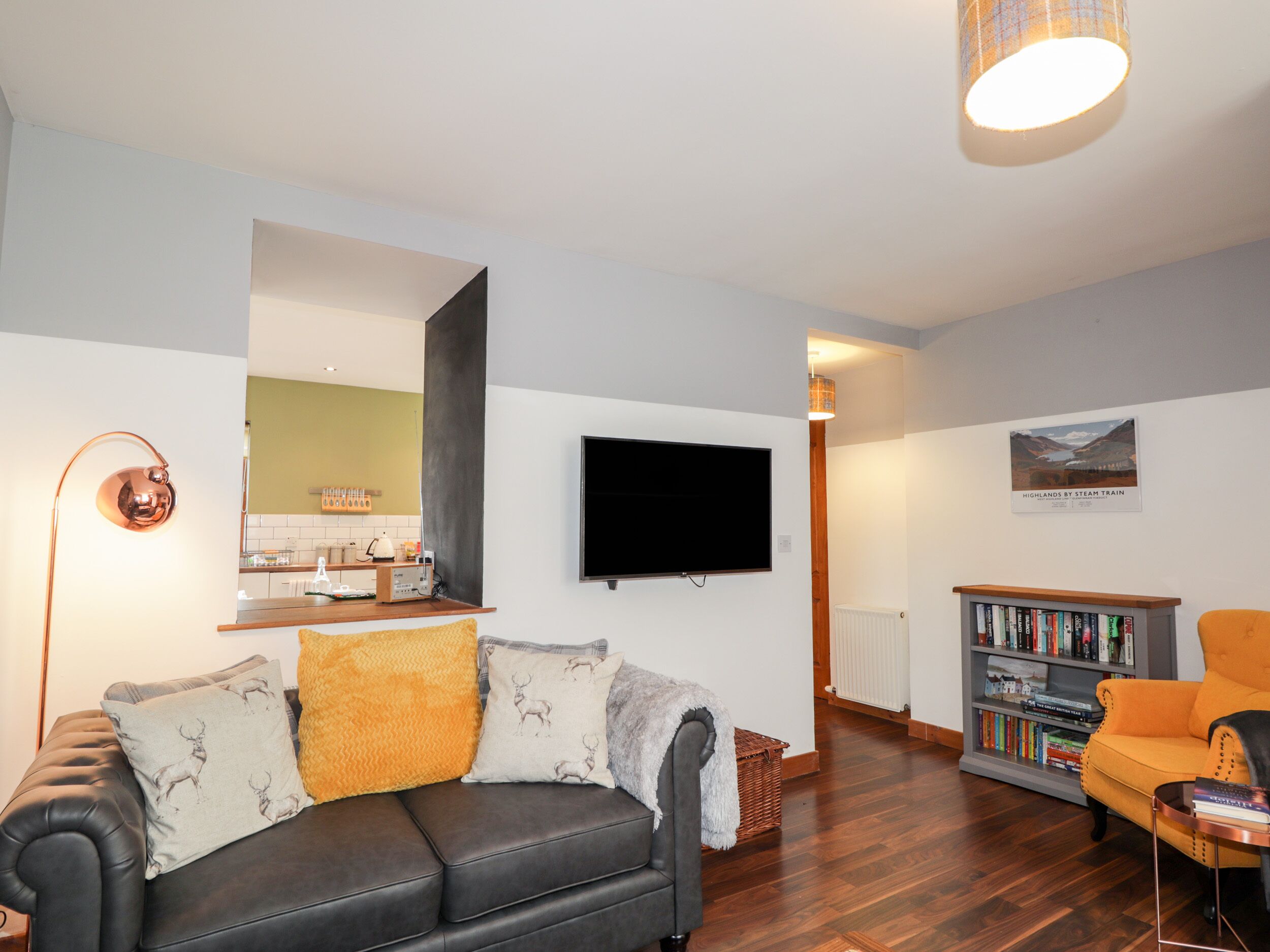 En stue med sofa, fjernsyn, bogreol og spiseplads med bord og stole.