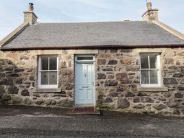 A stone house with a blue door, two windows, and a chimney.