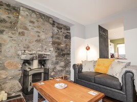 A cozy living room with a stone fireplace, a leather sofa, and a wooden coffee table.