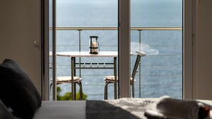 A balcony with a table and chairs, a candle, and a view of the sea.