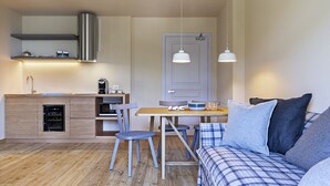A compact living space with a kitchenette, a dining area, and a seating area with a sofa and chairs. - QC Terme Panoramic Apartament (Valdidentro)