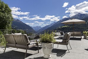 Una terraza con mobiliario exterior y una planta en maceta, con vistas a un paisaje montañoso.