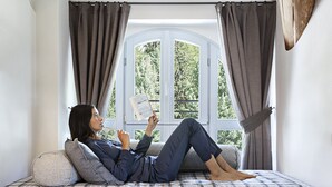 A person lying on a bed with a plaid bedspread, reading a book. - QC Terme Panoramic Apartament (Valdidentro)