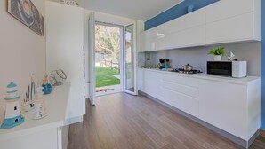 A modern kitchen with white cabinets, a microwave, and a small island with a plant. - Villa Il Gelsomino Bellavista (Besozzo)
