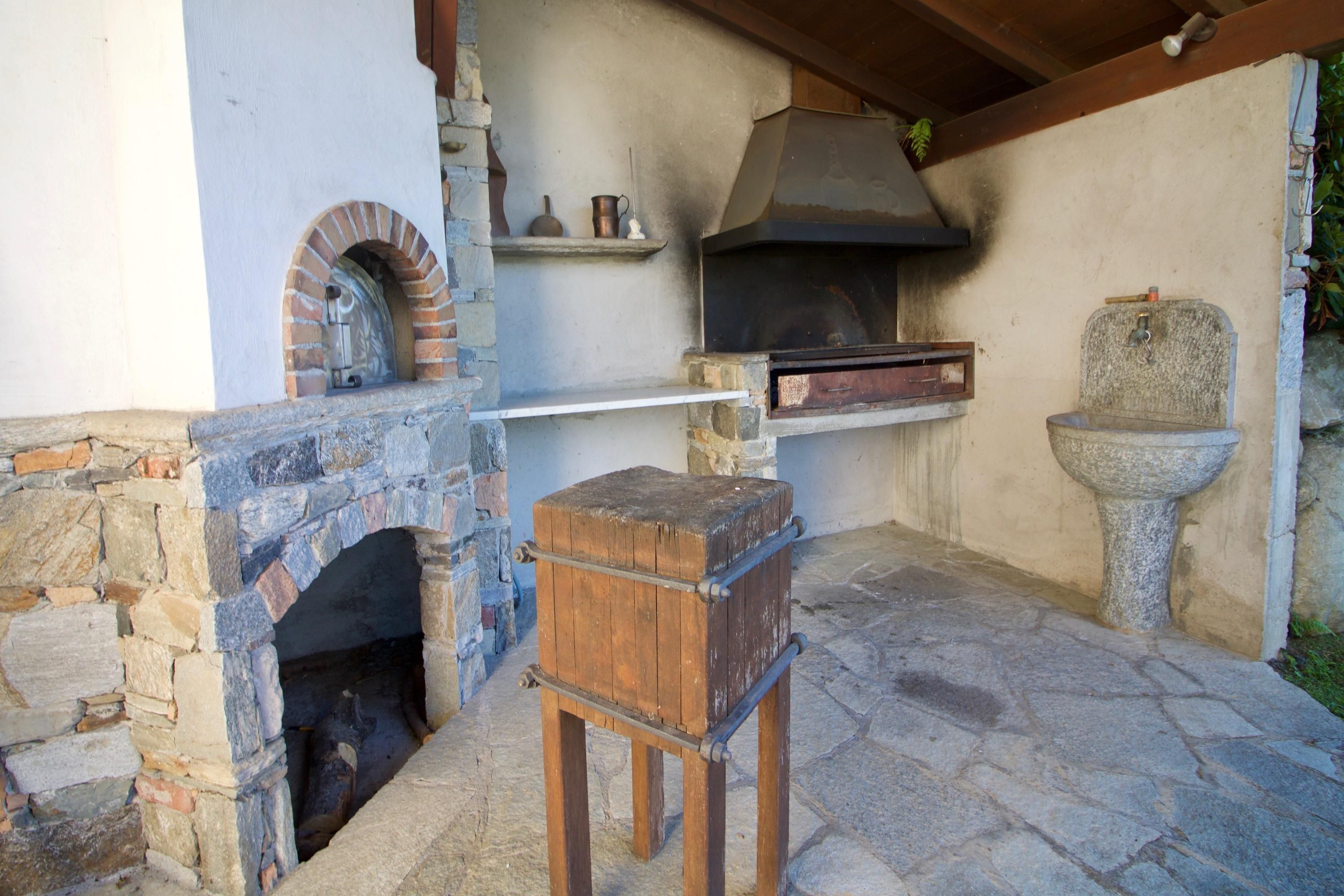 Una chimenea de piedra con un banco de madera en frente, un lavamanos de piedra y un horno de ladrillo.