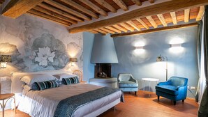 Ein Schlafzimmer mit einem Bett, einem Sessel, einem kleinen Tisch und einem Kamin.