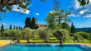 Piscina con vistas a un edificio histórico y árboles circundantes.