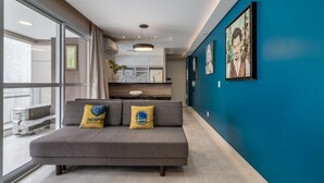 Una sala de estar moderna con un sofá gris, dos almohadas amarillas y una pared azul.
