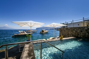 A clear blue sea with boats docked, a stone wall, and two white umbrellas. - Villa del Maggiore in Sorrento (Sorrento)