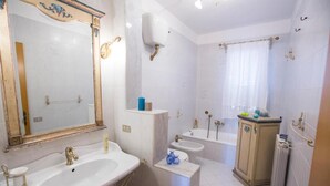 A bathroom with a large mirror, two sinks, a bathtub, and a radiator. - Seascape Terrace Spacious Apartment With Terrace (Cefalù)