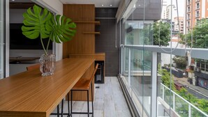 A modern dining area with a wooden table and chairs, a large green plant, and a view of the city through large windows. - Vi0301 in S o Paulo (São Paulo)