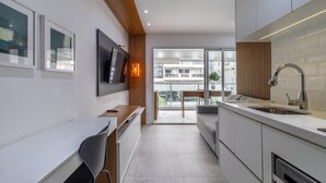 A modern kitchen with a built-in oven, a sink, and a dining area with a table and chairs. - Vi0301 in S o Paulo (São Paulo)