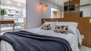 A modern hotel room with a large bed, a wooden headboard, a TV mounted on the wall, and a balcony with a view of the city. - Vi0301 in S o Paulo (São Paulo)