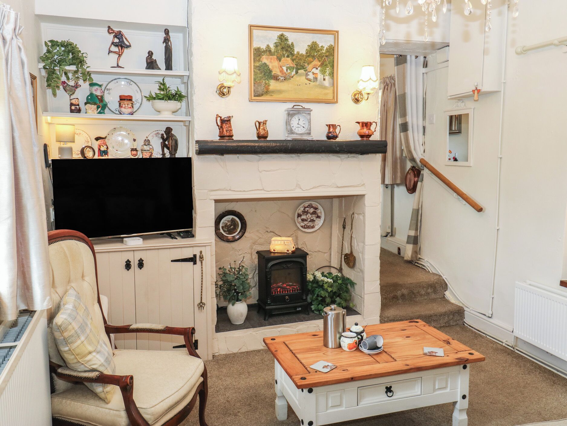 A cozy living room with a fireplace, a television, a comfortable armchair, and a coffee table.