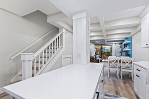 A modern kitchen with white cabinetry, a central island, and a staircase with white railings.