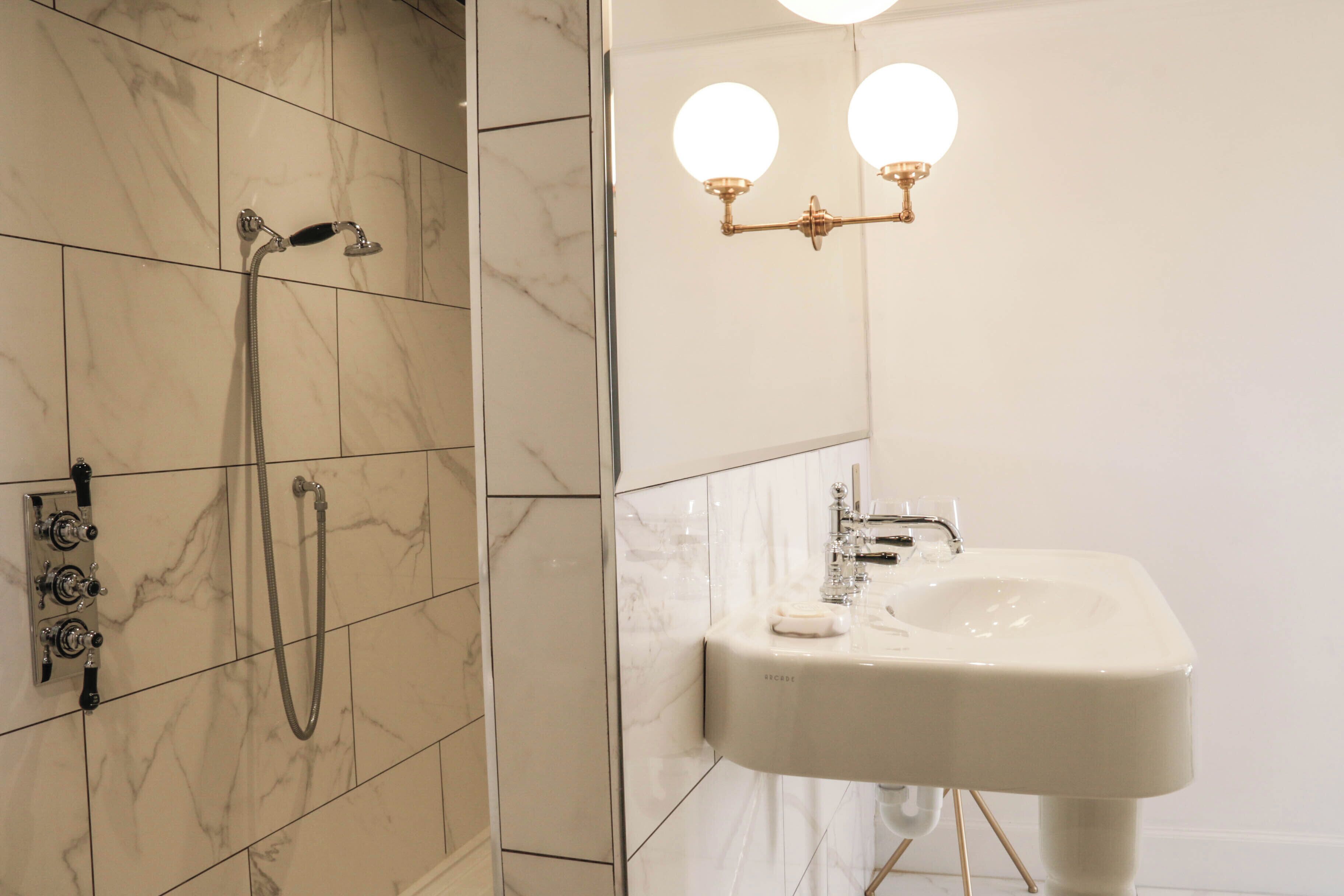 A bathroom with a shower, a sink, and a wall-mounted light fixture.