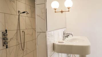 A bathroom with a shower, a sink, and a wall-mounted light fixture.