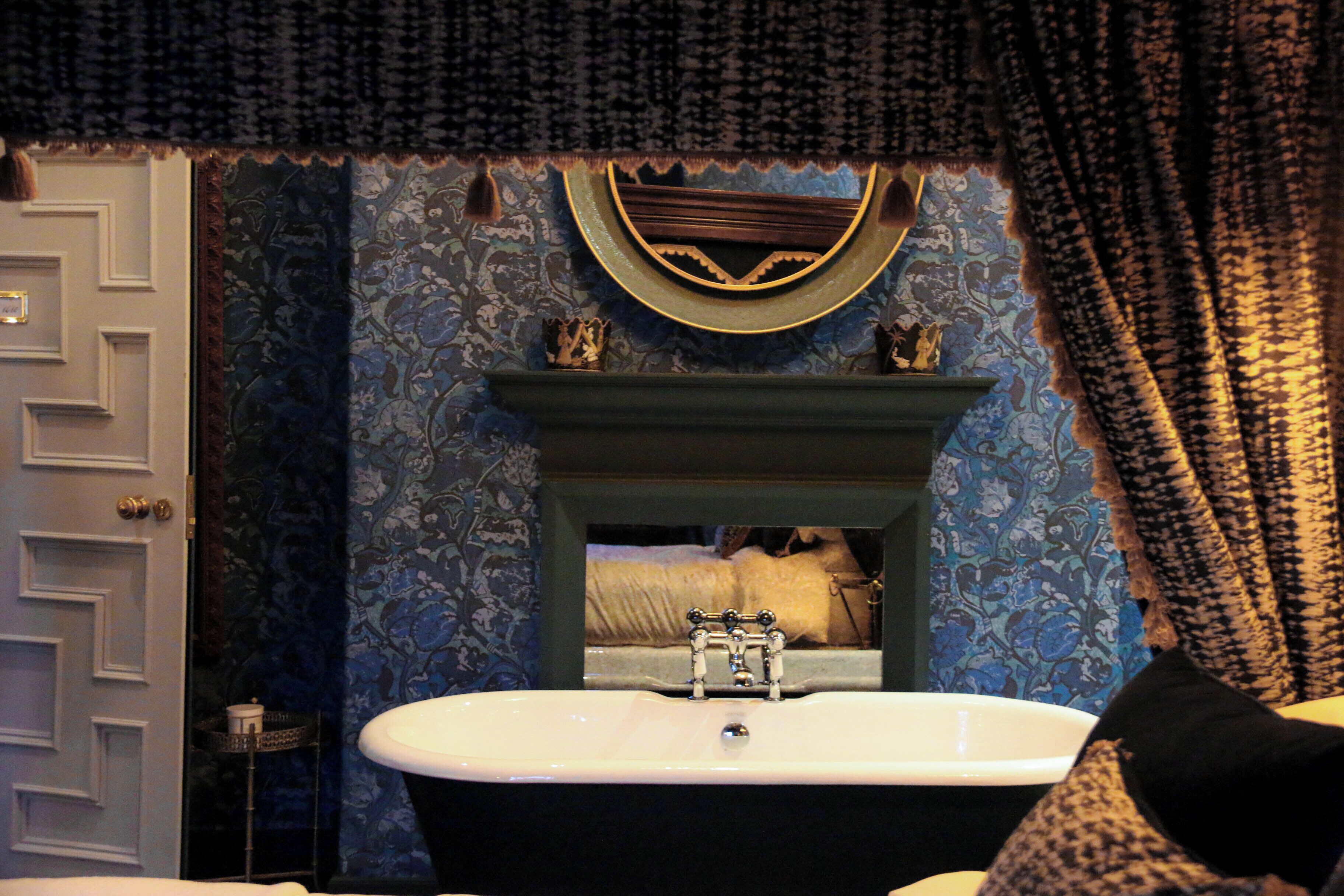 A bathroom with a white sink, a mirror above it, and a patterned wall.