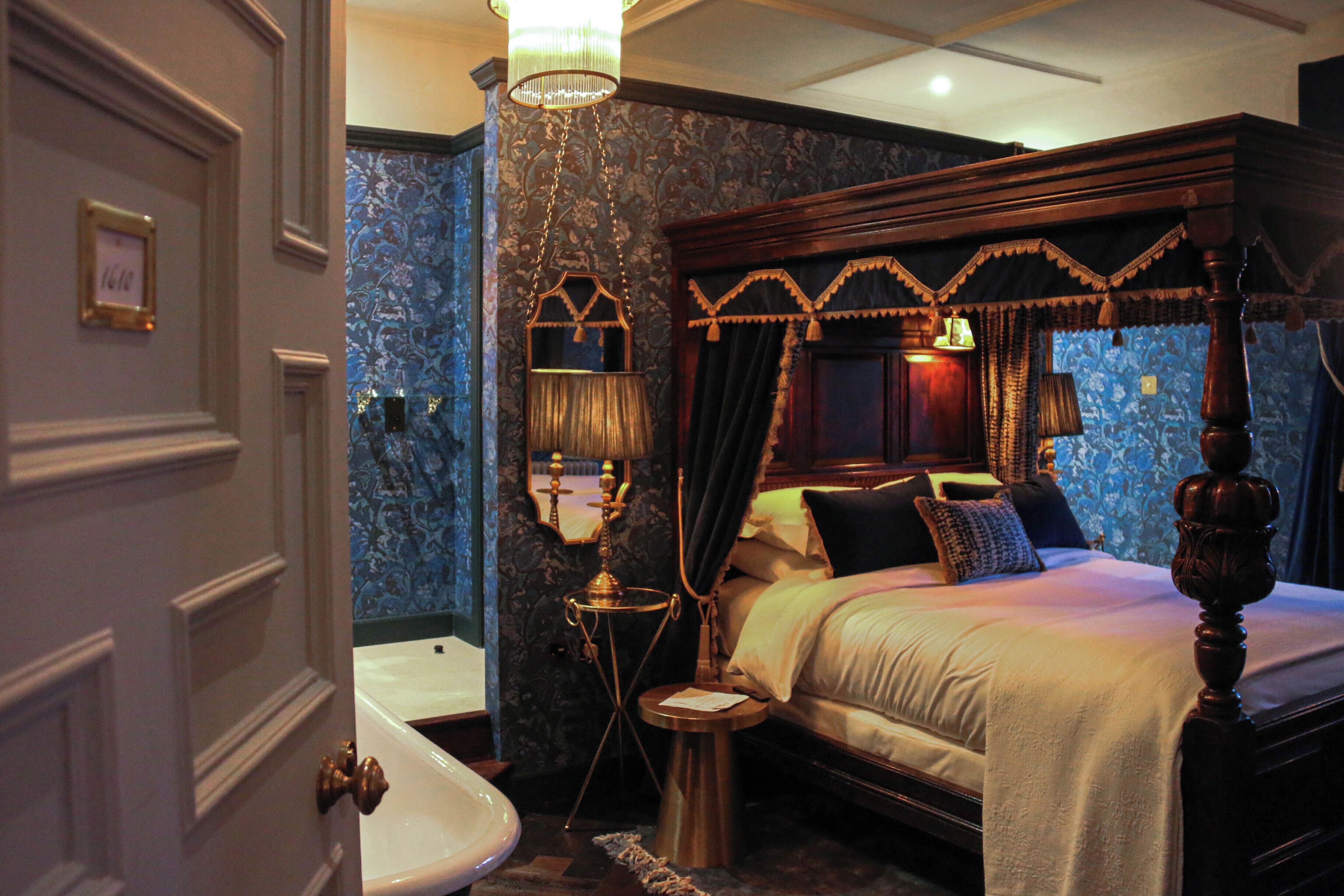 Une chambre à coucher avec un lit à baldaquin, un lustre, un miroir et une baignoire.