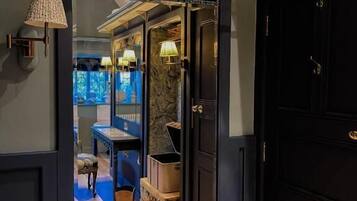 A dark wooden door with a brass handle, leading to a room with a wooden floor, a table, and a bench.