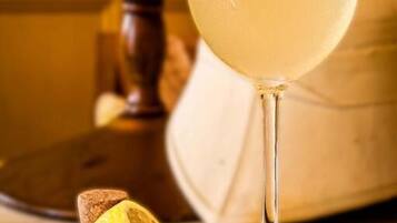 A glass of clear beverage with a lemon slice, a cork, and a wooden object in the background.