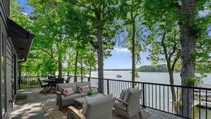 Una terraza con mobiliario exterior, una mesa de comedor y vista a un lago.