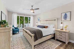 A bedroom with a bed, bedside table, nightstand, ceiling fan, and a view through a glass door. - Whiskey Sunsets: Stunning Peninsula Retreat with Panoramic Lake Views, Dock, Hot Tub, and More! (Mooresville)