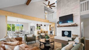 Amplia sala de estar con chimenea, comedor y cocina.