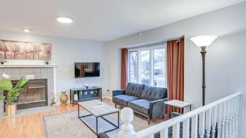 A living room with a fireplace, sofa, coffee table, and a TV mounted on the wall.