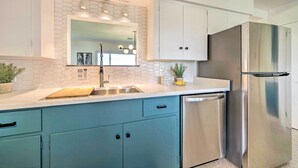 Una cocina moderna con un refrigerador de acero inoxidable, un lavamanos con protector contra salpicaduras hexagonal y armarios azul claro.