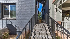 Eine Betontreppe mit schwarzen Geländern führt zu einem Hauseingang.
